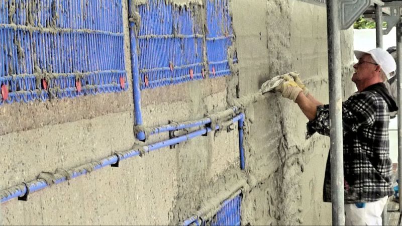 The capillary tube mats are applied to the outside of the facade as a surface heating system. In the picture, the adhesive mortar is being smoothed for the light plaster.