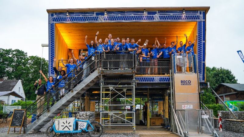 Jubelnde Studierende des Gewinner-Teams RoofKIT stehe auf der Treppe eines Demonstrationshaus auf dem Solar Campus in Wuppertal.