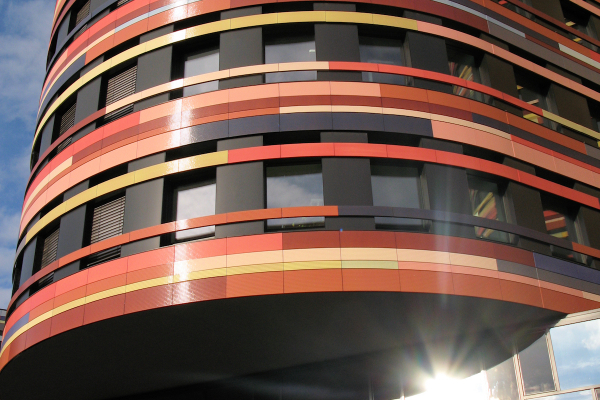 Die vielfältigen Farben der Keramikelemente bewegen sich im Spektrum von Rot-Gelb-Farbtönen am Turm bis hin zu Blau-Grün-Violett an den Enden der Gebäudeflügel.